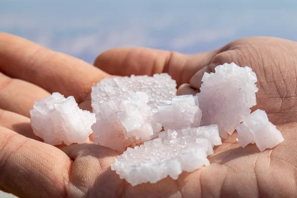 Hand Hält Ein Bündel Rosa Weißer Salzflocken Kristalle Über Wasser — Stockfoto