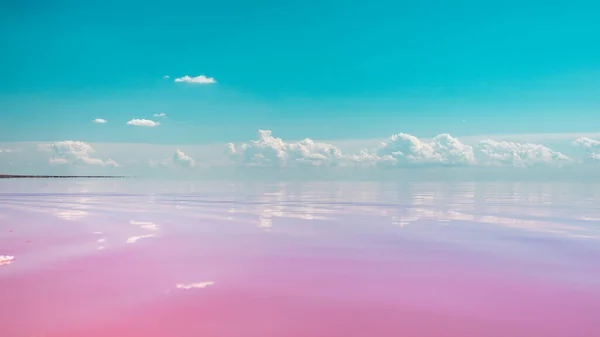 Pembe tuz gölü su yüzeyine yakın çekim mavi gökyüzü ile sihirli bulutların ayna yansıması, renk derecelendirmesi