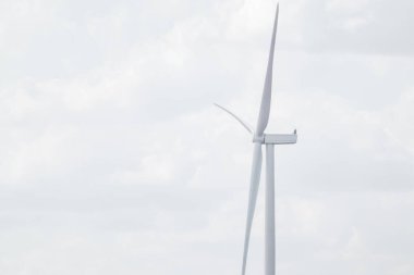 Çiftlik sürdürülebilir endüstrisinde rüzgar jeneratörü pervanesi yakın plan. Bulutlu gri gökyüzü enerji türbinleriyle bulutlu.