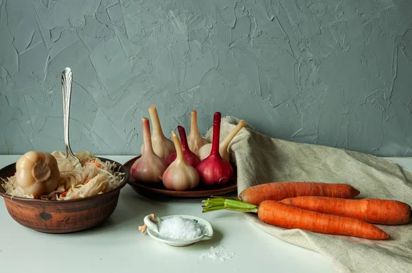 Капуста, маринованный чеснок, свежая морковь и грубая соль на белом столе — стоковое фото