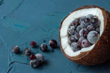 Mavi beton arka planda hindistan cevizi dondurulmuş çilek. Böğürtlenler döküldü.