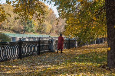 Kırmızı paltolu bir kadın sonbahar yürüyüşü boyunca yürür.
