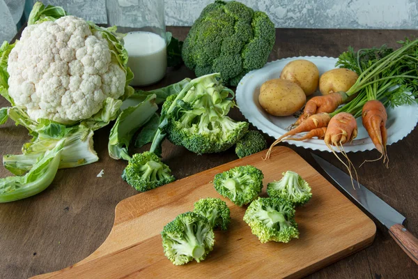 Bahan-bahan untuk membuat sup brokoli. Di atas meja adalah wortel, kembang kol dan kentang. — Stok Foto