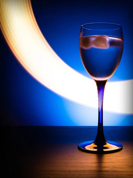 Copo Vinho Com Água Sobre Fundo Azul Com Linhas Luminosas — Fotografia de Stock