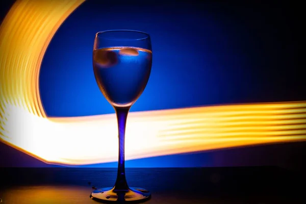 Copo Vinho Com Água Sobre Fundo Azul Com Linhas Luminosas — Fotografia de Stock