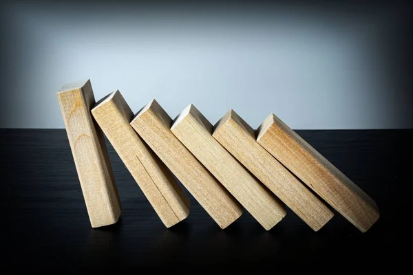 A wooden block stops the fall of other parts of the domino effect. Business risk management concepts.