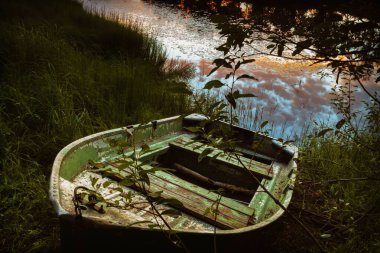 Günbatımında Reed River Sahili ve eski balıkçı teknesiyle sakin bir akşam manzarası.