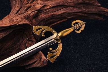 Şövalyenin kılıcı arka planda, kahverengi renkli eski ahşap bir dalda.