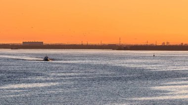 Bir tekne ve gün batımında süzülen kuşlarla nehir manzarası. Güzel akşam manzarası.