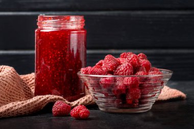 Mason kavanozunda ev yapımı organik ahududu reçeli. Mevsimlik koruma tatlısı. Klasik ahşap masa arka planı. Kırsal tarz ve doğal ışık. Siyah yemek fotoğrafı..