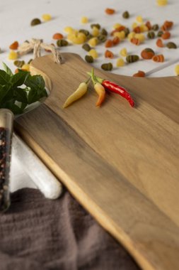 Kırmızı biber, turuncu ve sarı tahta kesme tahtasında.