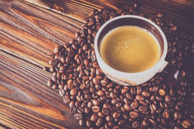 Tahta arka planda bir fincan kahve ve kahve çekirdeği.