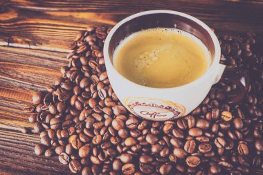 Tahta arka planda bir fincan kahve ve kahve çekirdeği.