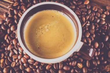 Tahta arka planda bir fincan kahve ve kahve çekirdeği.