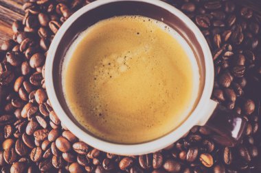 Tahta arka planda bir fincan kahve ve kahve çekirdeği.