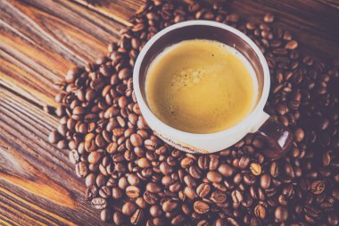 Tahta arka planda bir fincan kahve ve kahve çekirdeği.