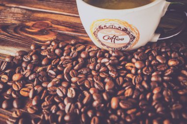 Tahta arka planda bir fincan kahve ve kahve çekirdeği.