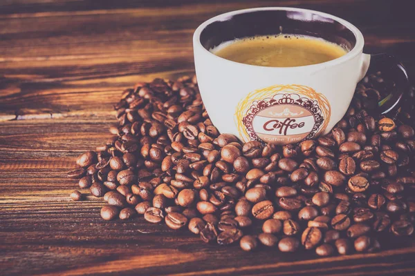 Tahta arka planda bir fincan kahve ve kahve çekirdeği.
