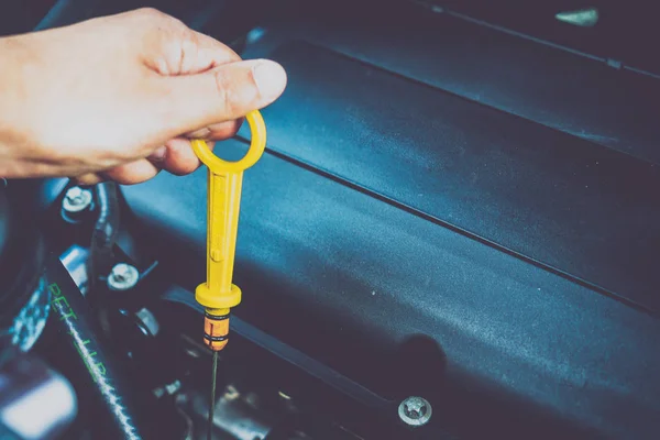 The hand checks the oil in the engine