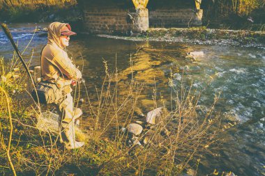 Balıkçı bir alabalık bir dağ nehir üzerinde yakalar.