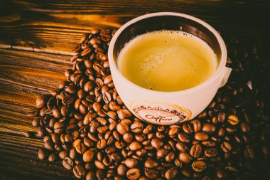 Tahta arka planda bir fincan kahve ve kahve çekirdeği.