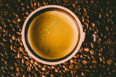 Tahta arka planda bir fincan kahve ve kahve çekirdeği.