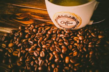 Tahta arka planda bir fincan kahve ve kahve çekirdeği.