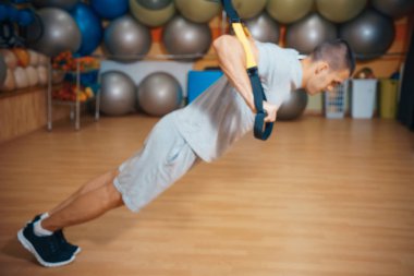 Genç adam bir spor salonunda trx devreye girer
