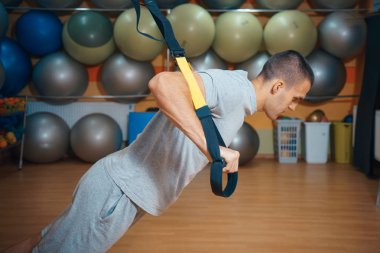 Genç adam bir spor salonunda trx devreye girer