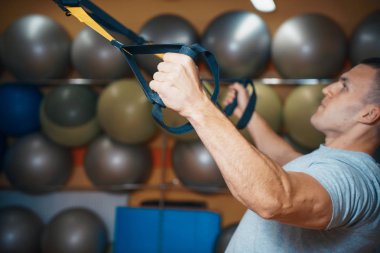 Genç adam bir spor salonunda trx devreye girer