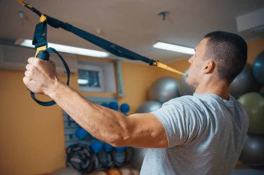 Genç adam bir spor salonunda trx devreye girer