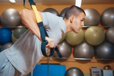 Genç adam bir spor salonunda trx devreye girer