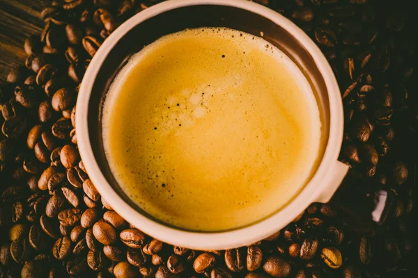 Tahta arka planda bir fincan kahve ve kahve çekirdeği.