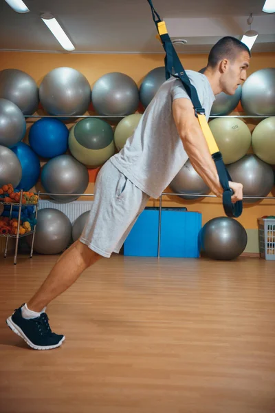 Genç adam bir spor salonunda trx devreye girer