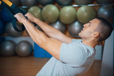 Genç adam bir spor salonunda trx devreye girer