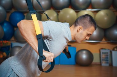 Genç adam bir spor salonunda trx devreye girer