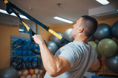 Genç adam bir spor salonunda trx devreye girer