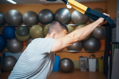 Genç adam bir spor salonunda trx devreye girer