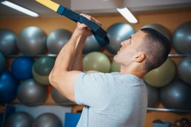 Genç adam bir spor salonunda trx devreye girer