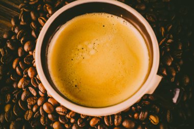 Tahta arka planda bir fincan kahve ve kahve çekirdeği.