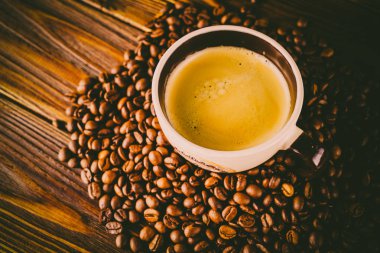 Tahta arka planda bir fincan kahve ve kahve çekirdeği.