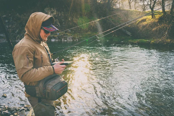 Balıkçı bir alabalık bir dağ nehir üzerinde yakalar.