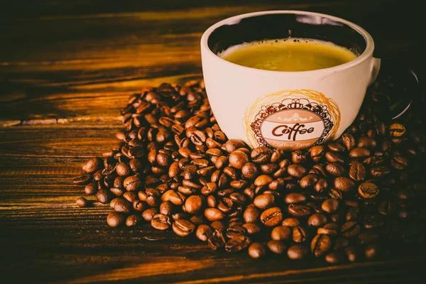 Tahta arka planda bir fincan kahve ve kahve çekirdeği.