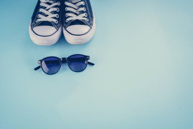 Spor ayakkabı, gözlük mavi bir arka plan üzerinde