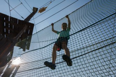 Çocuk ip parkında oynuyor.