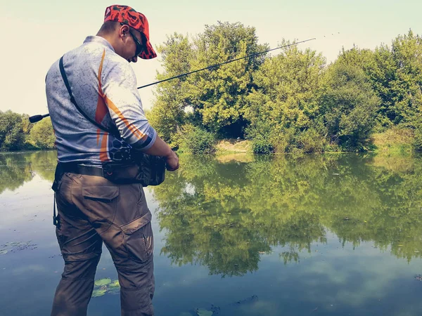 O pescador está pescando no lago no verão — Fotografia de Stock