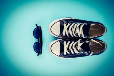 Spor ayakkabı, gözlük mavi bir arka plan üzerinde