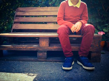 şık çocuk ahşap bir bankta oturur