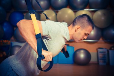 Genç adam bir spor salonunda trx devreye girer