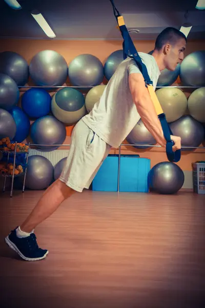 Ung man är engagerad i ett gym i trx — Stockfoto